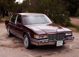 Luxury Cadillac DeVille parked outdoors on a sunny day, showcasing its classic design and elegance.